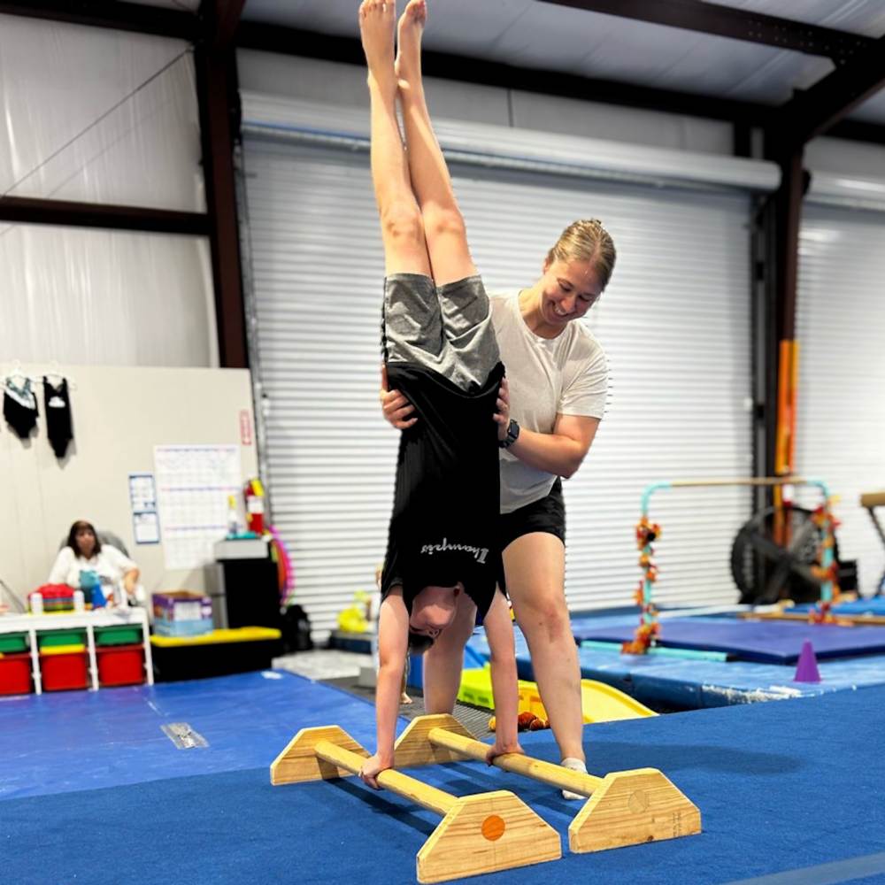 Jill Gray assisting a student with handstand