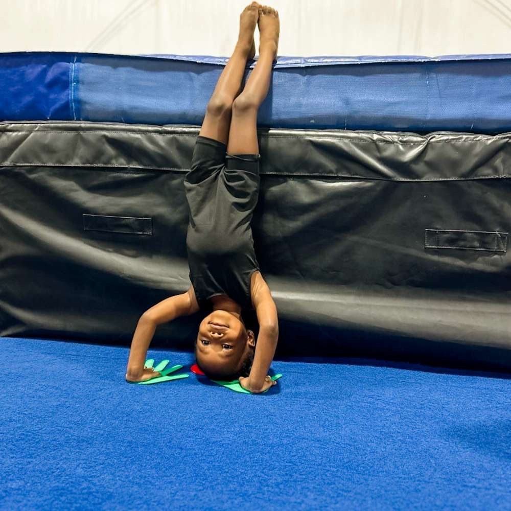 Toddler girl doing headstand against mats