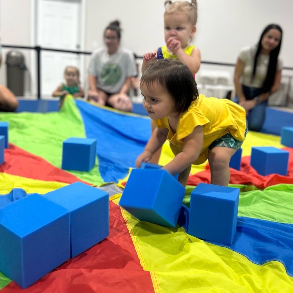 toddlers playing with foam blocks on parachute